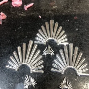 Silver sunburst-shaped castings laid on a dark bench