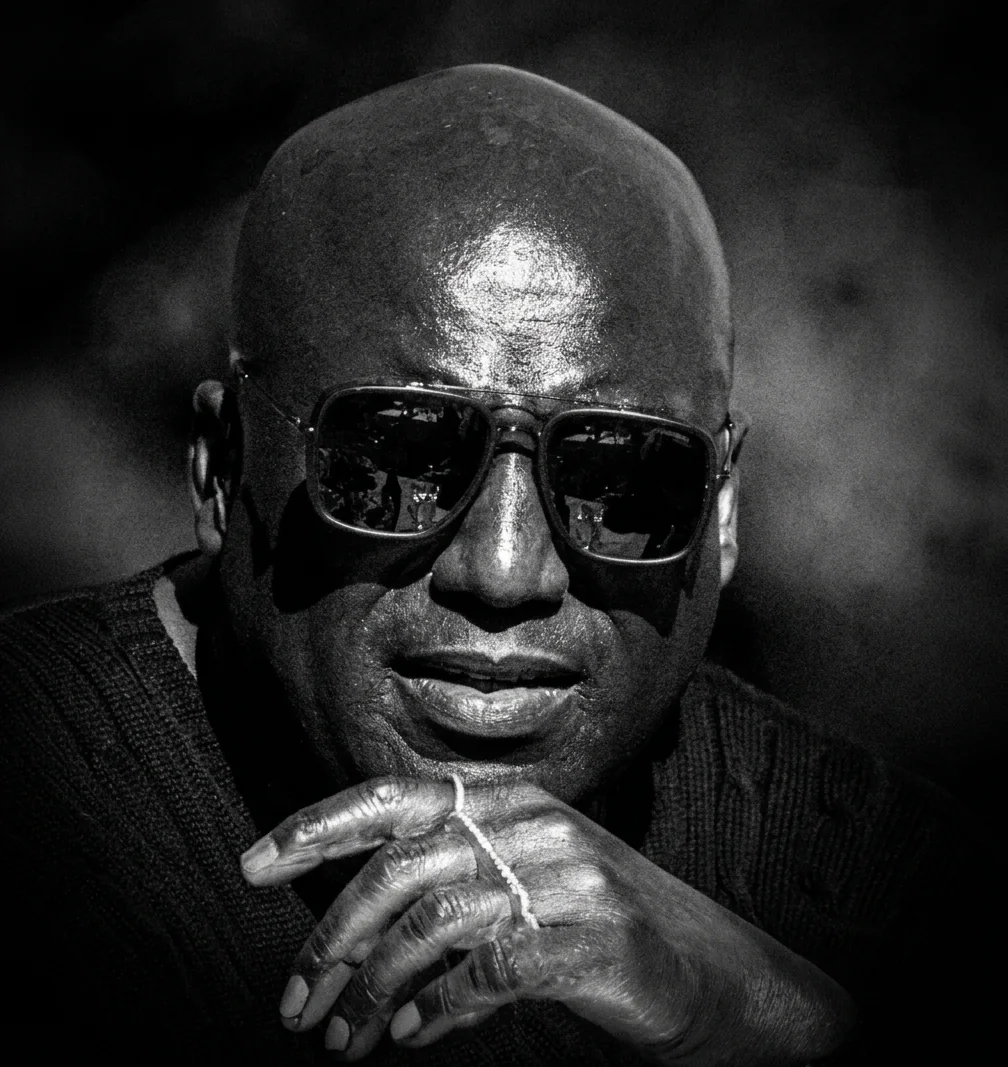 Black and white portrait of Kenly Warren in sunglasses, chin resting on his hand