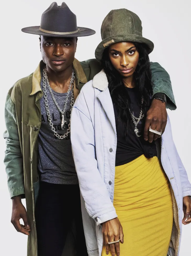 Two models in hats wearing heavy silver chains and rings