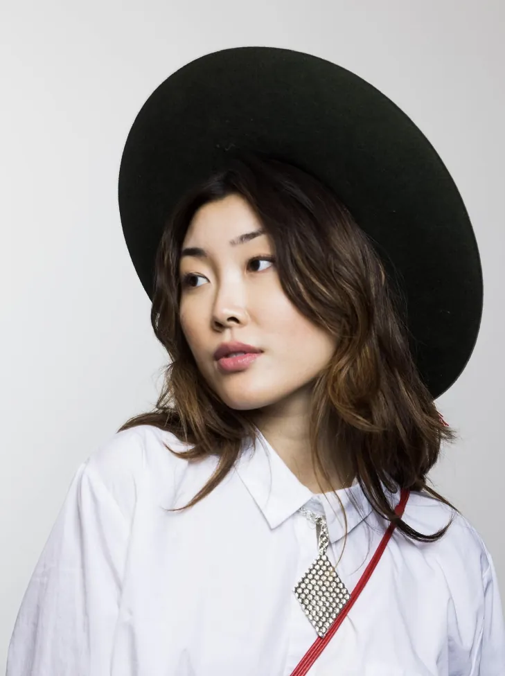 Model in a wide black hat and white shirt wearing a diamond-pendant lariat