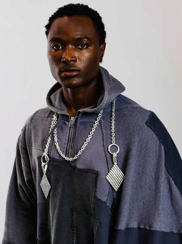 Model in a patchwork hoodie wearing heavy chains with diamond pendants