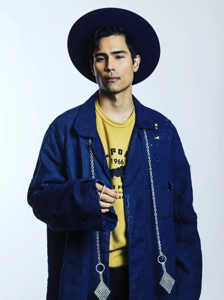 Model in an indigo coat and hat wearing a long lariat