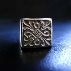 Square signet-style ring with an ornate raised motif